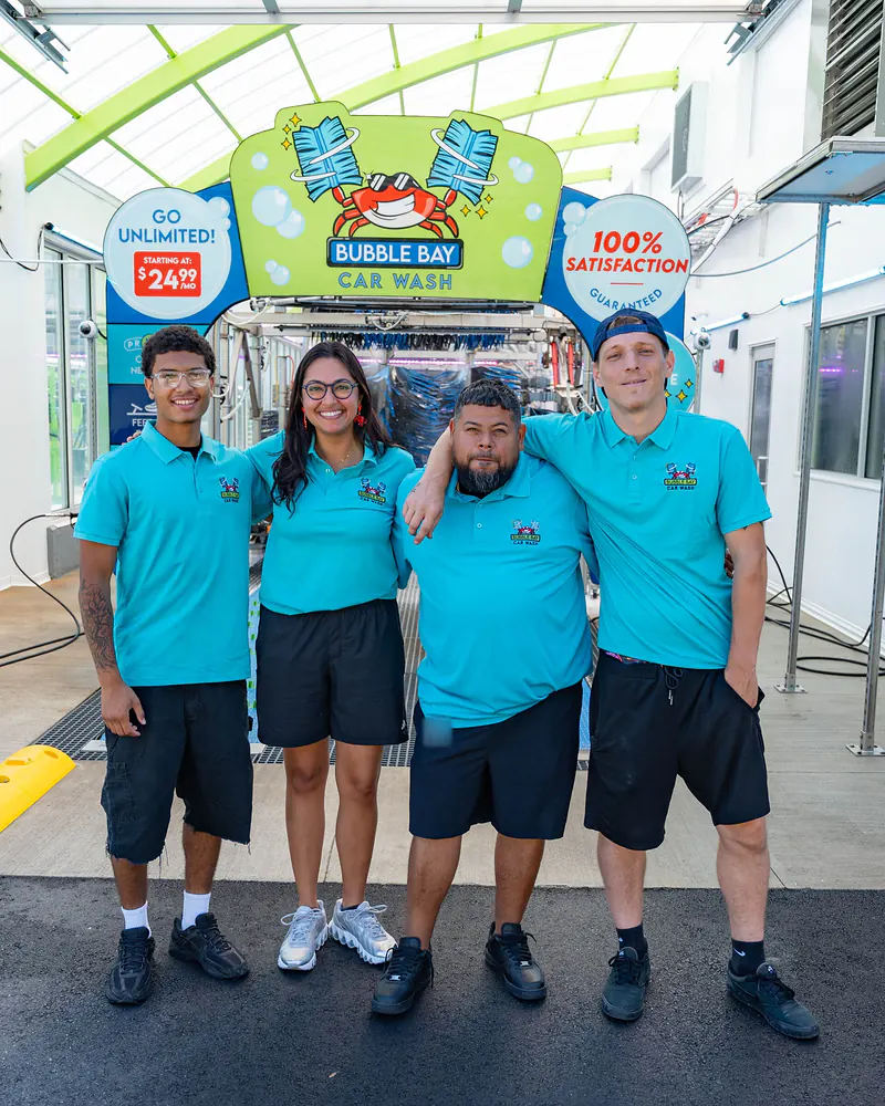 Four Bubble Bay team members in teal shirts at the entrance to the Haverhill wash